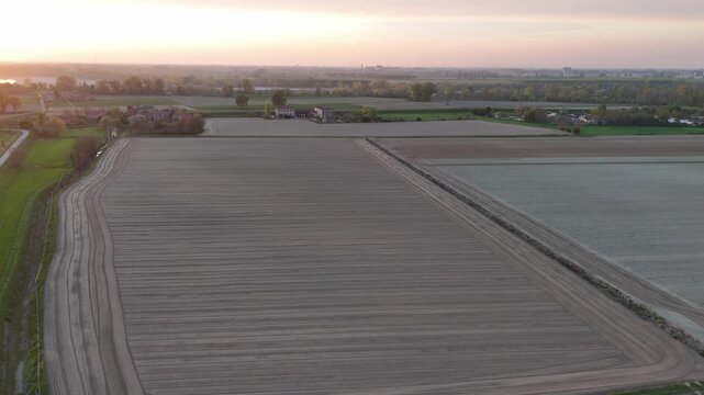 Agricultural fields with parallel cultivation furrows, tractor tracks and rural farm buildings near Monticelli d'Ongina and Castelvetro Piacentino, Piacenza, Emilia-Romagna, Italy, aerial view