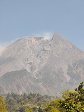 Mount Merapi Volcano Rising Above Forested Foothills In Central Java Or Yogyakarta Under A Hazy Morning Sky