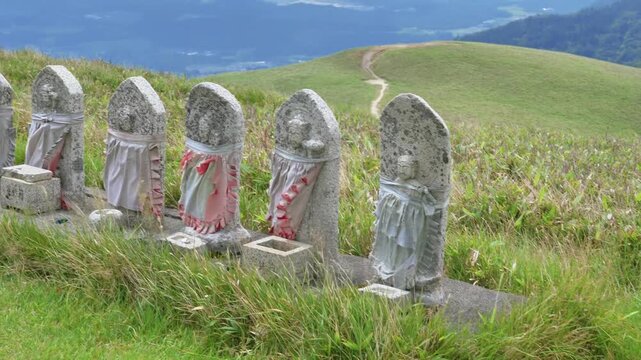 Row of stone Jizo statues with red bibs on top of mountain at Biwako Valley in Shiga Japan