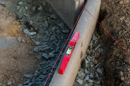A leveling tool is placed atop a concrete block, aligning with marked string lines for precise measurement.