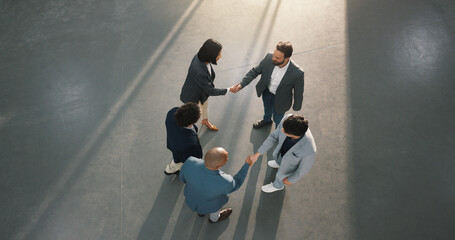 Above, lobby and business people with handshake for meeting, agreement and real estate deal. Office, realtor and workers shaking hands for commercial development, welcome and property negotiation © peopleimages.com
