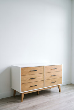 Mid century dresser with oak drawers against white wall