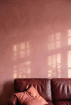 Textured living room wall with leather sofa and window shadows