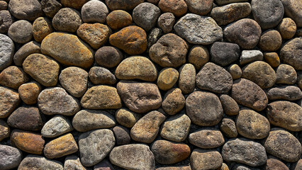 A textured wall made of multicolored, rounded pebbles and natural stone. A natural texture for landscape design, architectural projects, and decorative finishes. © Lisi4ka