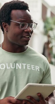 Volunteer, discussion or black man outdoor with tablet, task briefing or schedule in charity project. Happy, talk or NGO worker with tech, director coordination or appointing duty in outreach program