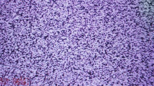 An old television, turned on but with no signal, gray static moving, varying in its image, a square, large, and well-maintained television