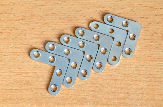 Metal brackets arranged in a line on a wooden surface for construction projects