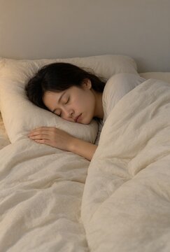 Woman sleeping on her side beneath a soft cotton duvet