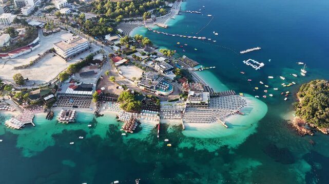 Drone video captures a bustling, sunlit beach lined with umbrellas and dense crowds along turquoise waters, highlighting tourism&rsquo;s dramatic pressure on vulnerable coastal habitats.