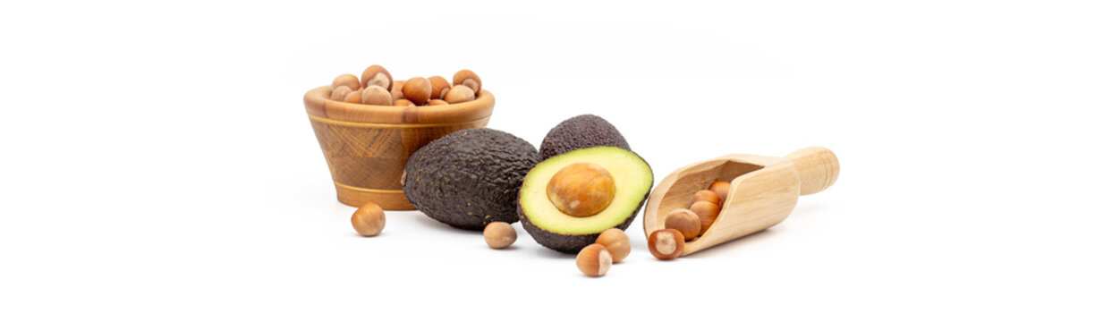 Fresh avocados and hazelnuts in wooden bowls on a white background   