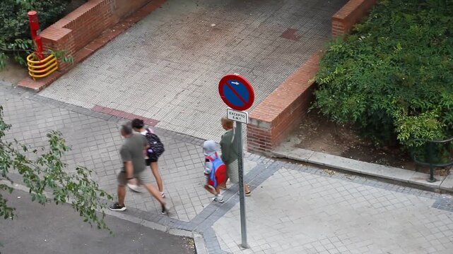 Llevar al colegio padres con ni&ntilde;os camino del cole con mochila a estudiar educaci&oacute;n infantil, conciliar, aprender y madrugar caminar por la calle vuelta al cole 