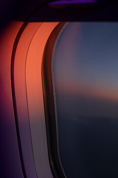 Abstract close-up of airplane window glowing in red and violet light