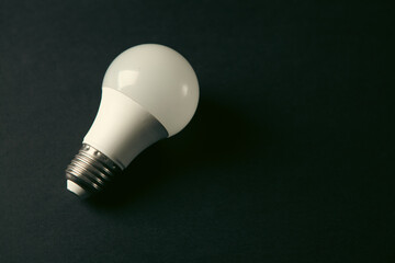 Energy saving light bulb on black background. Energy saving concept. Toned. © Artvibe