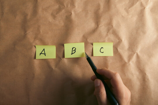 Hand writing ABC on sticky notes on crumpled paper, closeup