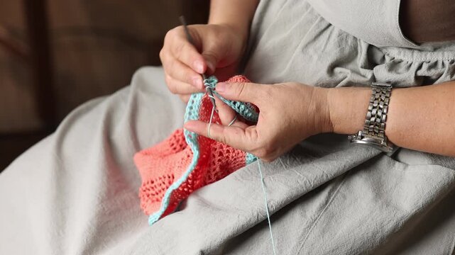 Woman crochets bag made of knitted blue pink threads. Engaging hobby	