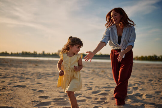 Mother and daughter running and playing on beach