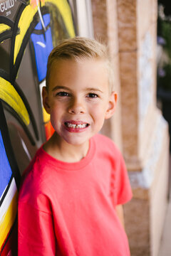 Happy little boy with a gap tooth smile by a mural