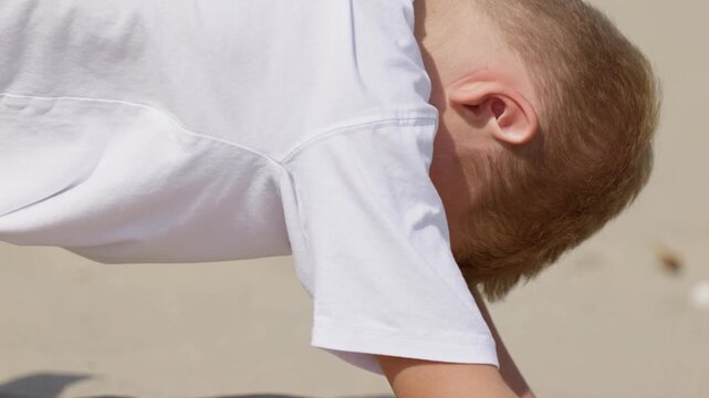 A boy is digging a hole in the sand slow motion close-up shot