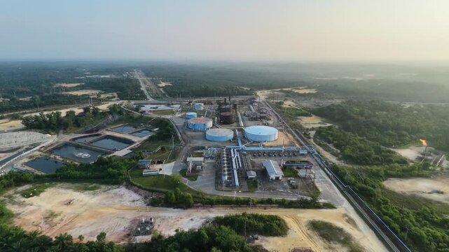 aerial landscape of a crude oil and natural gas processing plant with storage silos and pipeline networks at sunset. Industrial economy, power generation, and fuel supply.