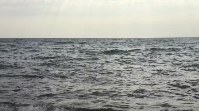 A wide, minimalist view of the open sea under an overcast sky.