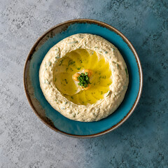 Fototapeta premium Hummus Beiruti with Olive Oil, Chickpeas and Herbs on a Turquoise Plate