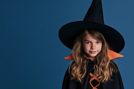 young child wearing Halloween witch costume, isolated on blue background with copy space