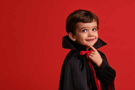 young child wearing Halloween vampire costume, isolated on red background with copy space