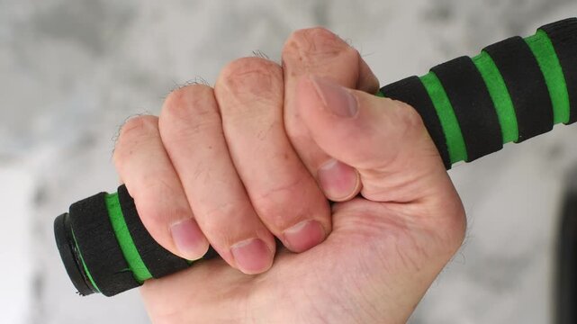 A hand wraps around a pull-up bar with black and green foam grip, tightening its hold in close-up.