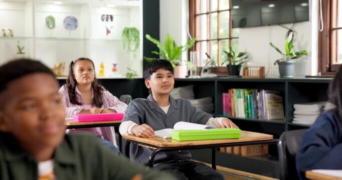 Preteen, education and student with raised hand in classroom, talk and learning for academic growth. School, knowledge and happy boy with answer for question, development and participation for lesson