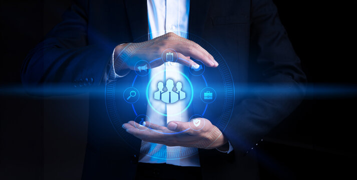 Business professional presenting a futuristic digital human resources interface featuring a group of employees and organizational icons. The concept represents human resource management, recruitment, 