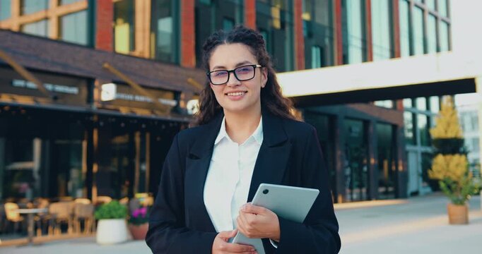 Portrait of a confident young businesswoman smiling at the camera in front of a modern office building