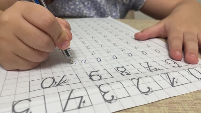 Close up of little child hand tracing zero digits on paper math worksheet during preschool handwriting preparation for school stock footage.
