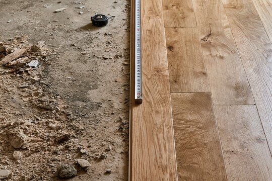 Wood flooring installation with measuring tape on subfloor