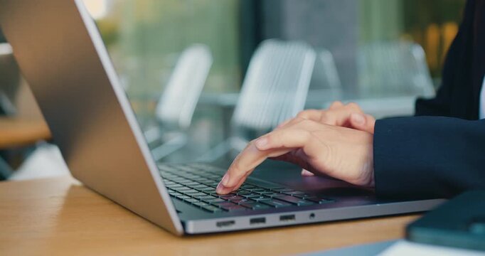 Close-up of female professional hands typing on a laptop while working online in a city setting, outdoors. Concept of finance, corporate business, digital banking, fintech technology, and modern