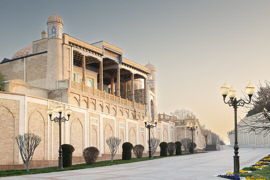 Hazrat Khizr mosque in Samarkand with ornate brick facade and carved wooden veranda along an empty boulevard. Ideal for travel guides, cultural publications, and tourism marketing materials.