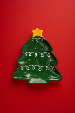 Christmas tree shaped ceramic plate with yellow star on vertical red background for holiday decor