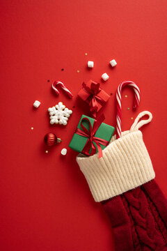 Christmas stocking filled with gifts, candy canes and festive decorations for Merry Christmas and Happy New Year on vertical red table