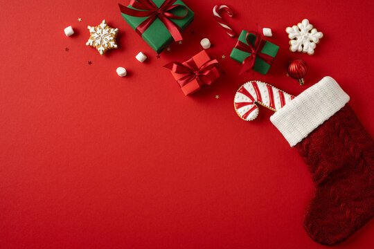 Merry Christmas and Happy New Year red stocking with gifts cookies and candy cane on wide red background