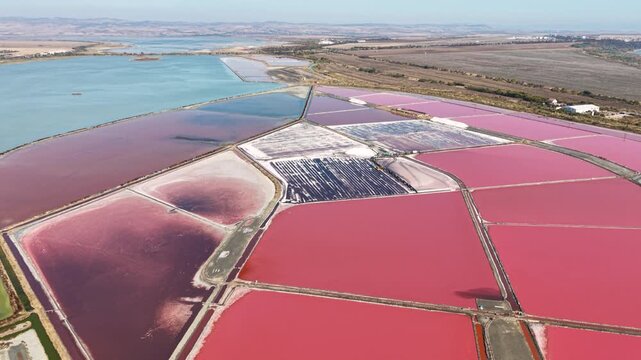 Aerial view of the vibrant pink salt pans with geometric dikes and industrial infrastructure in Burgas, Burgas, Bulgaria.