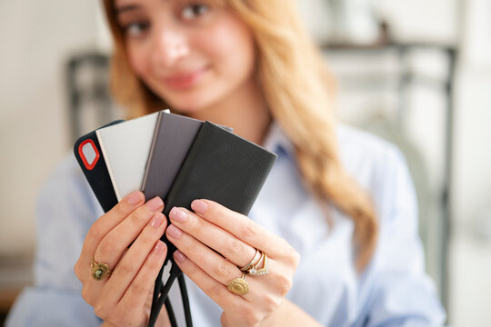 A young woman with blond hair holds multiple portable external solid-state drives in her hands. She displays the compact data storage devices in an indoor setting.