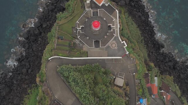 Arnel lighthouse illuminating sao miguel island coastline ascending shot