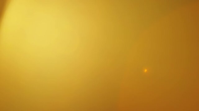Bright orange-gold lens flare floods the frame with light and small optical ghost reflections, creating an abstract texture for cinematic overlays, flash transitions, compositing and vintage edits.