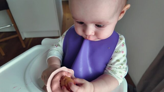 Cute 7-8 month old baby Macro close up shot of cute baby in purple silicone bib chewing soft teether toy. Teething process, itchy gums relief, infant sensory play, pediatric care, and home feeding mom