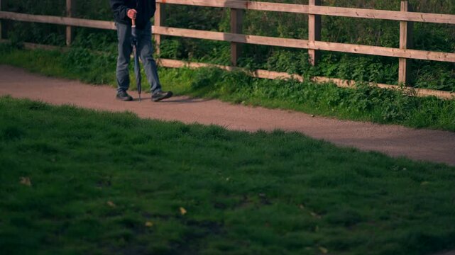 An unidentifiable elderly gentleman walking along a trail 