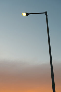 Glowing street lamp post illuminated against a beautiful gradient sunset sky.