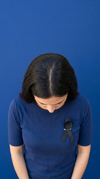 Woman wearing black mourning ribbon bowed head symbol of grief loss solidarity sympathy remembrance