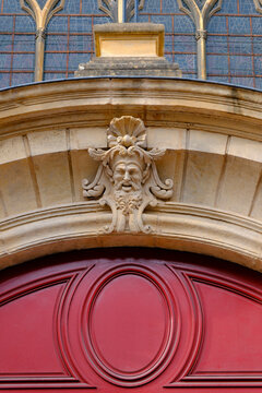 Saint Vincent Basilica, Metz, Moselle, France. A carved stone mascaron adorns the keystone above a molded door painted red.
