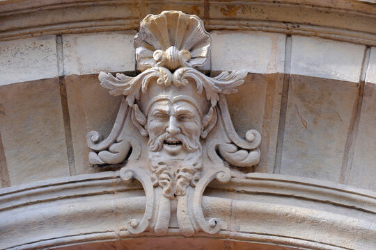 St. Vincent Basilica, Metz, Moselle, France. This carved stone mascaron adorning the keystone of an arch features a bearded, expressive face topped by a seashell.