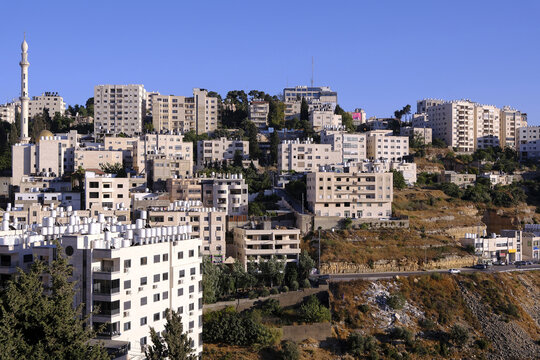 Panoramic view of Ramallah in Palestine, featuring its light-colored stone buildings, a minaret, and water tanks.