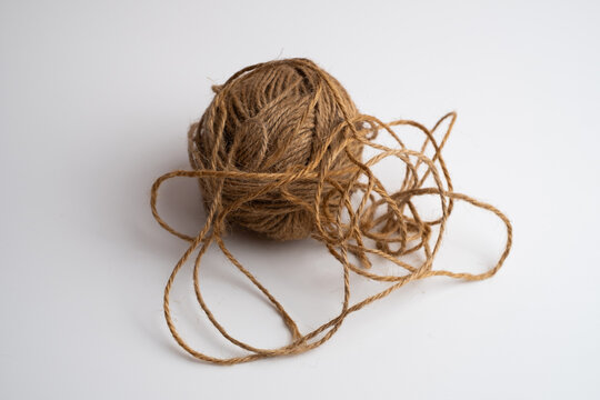 Tangled ball of brown jute twine with loose loops on white background, natural rope string for craft and packaging, copy space